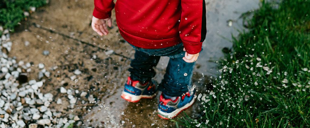 Boy jumping into a puddle