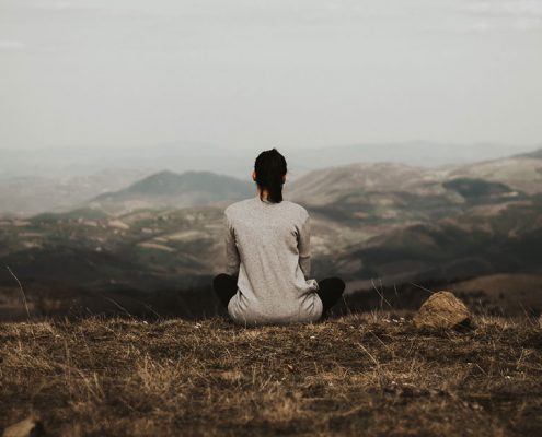 Woman sitting alone thinking on a mountain