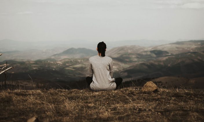 Woman sitting alone thinking on a mountain