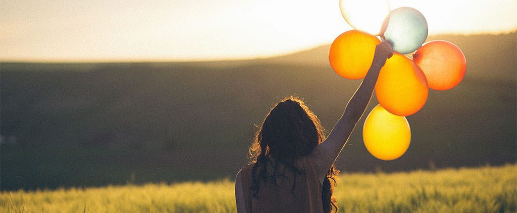Woman holding balloons in an open field