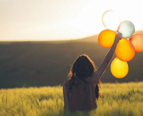 Woman holding balloons in an open field