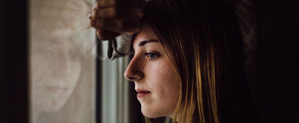 Woman with her forehead pressed against a window