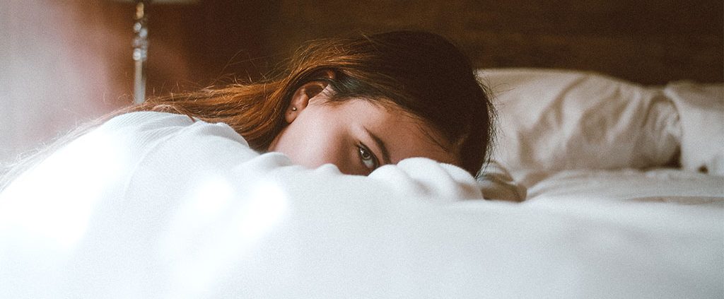 Woman on her knees resting her head on a bed