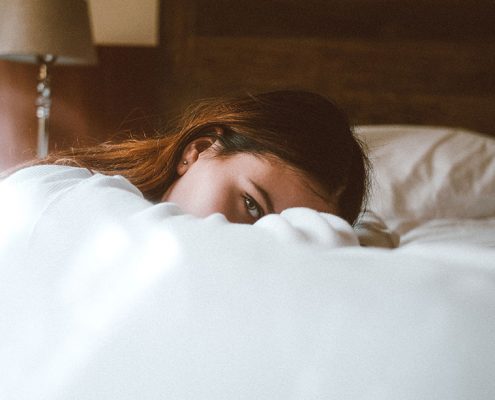 Woman on her knees resting her head on a bed