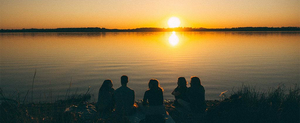 Family sitting by the water watching the sunset