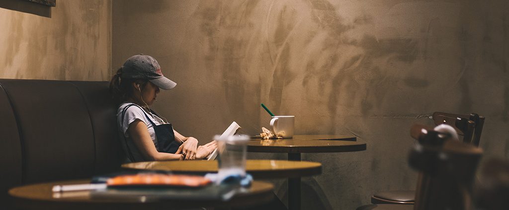 Girl alone reading in a coffee shop