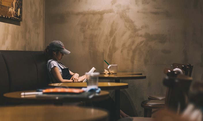 Girl alone reading in a coffee shop