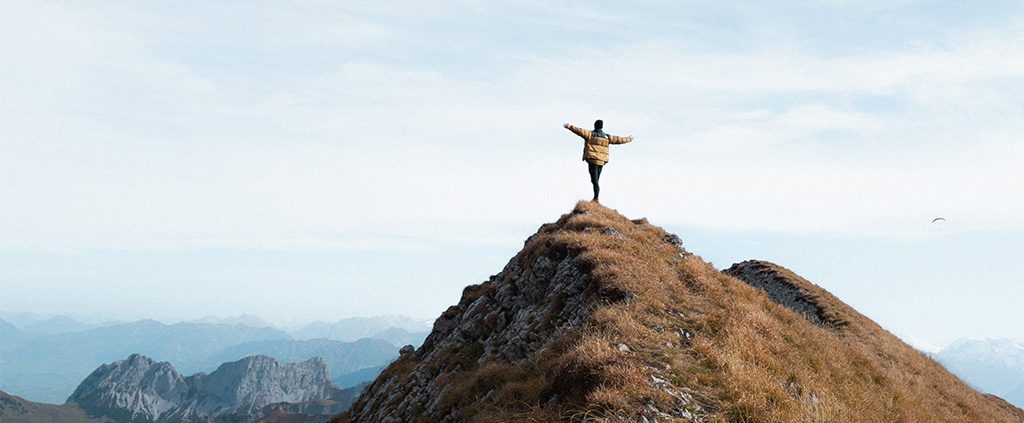 Person on top of the mountain with their hands out wide