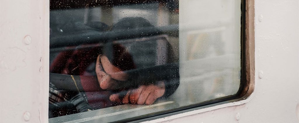 Person with their head down on a rainy train ride