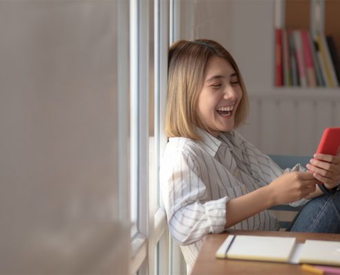 Girl sitting down laughing at her phone