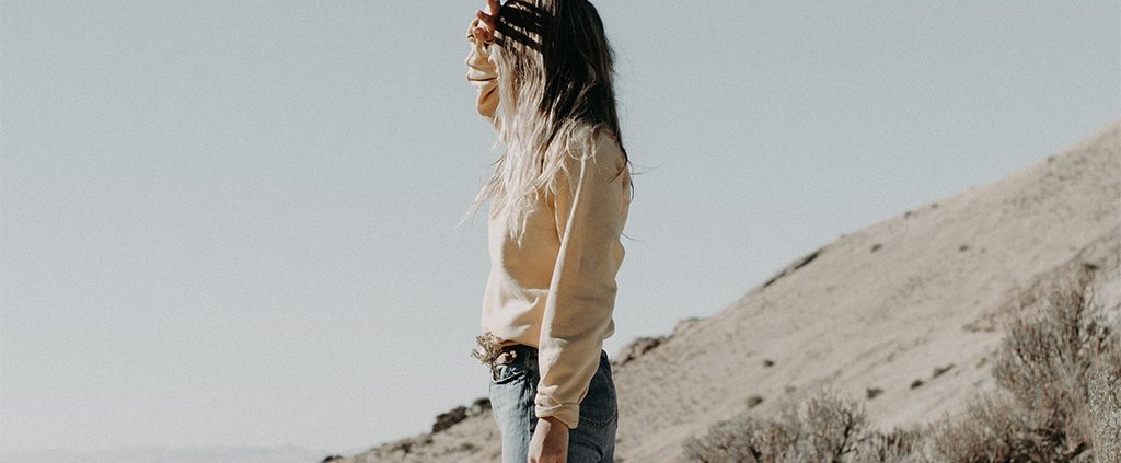 Girl blocking the sun with her eyes on a mountain