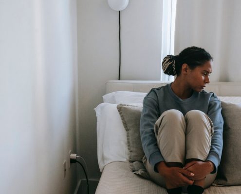 Woman sitting in bed sad and alone - is loneliness a sin