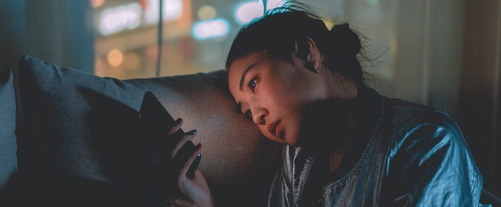 Woman sitting on her couch staring at her phone