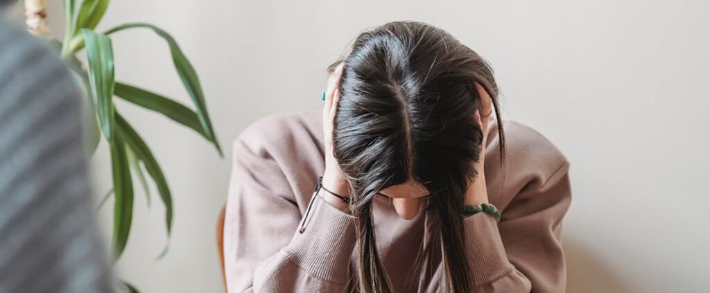 Woman sitting down with her head in her hands upset