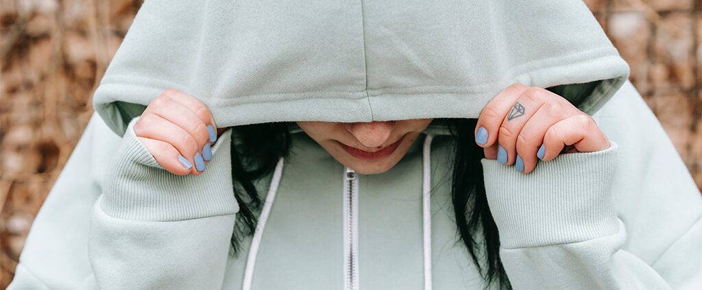 A sad woman covered her face with her hoody jacket