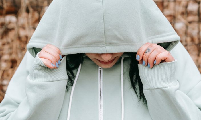 A sad woman covered her face with her hoody jacket
