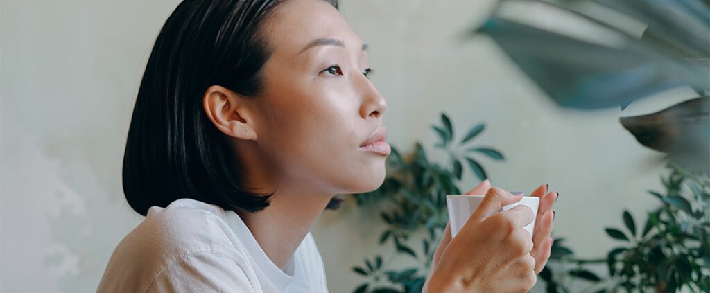 Image of a girl thinking and holding a cup of coffee