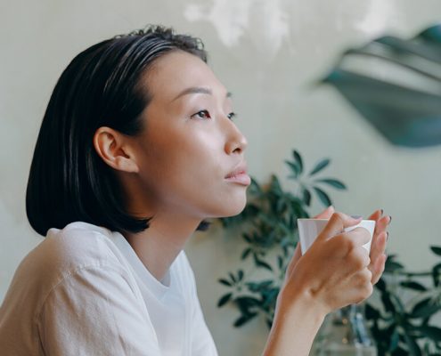 Image of a girl thinking and holding a cup of coffee