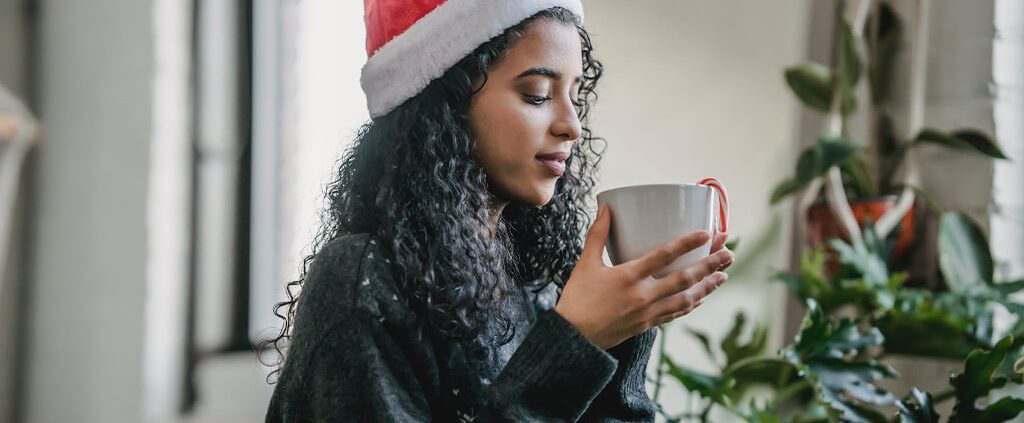 Woman sipping coffee in a santa hat