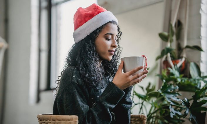 Woman sipping coffee in a santa hat