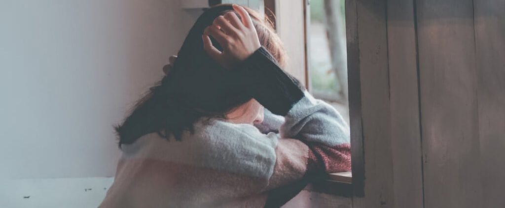 A woman looking out of the window with a mixed feeling during Christmas.