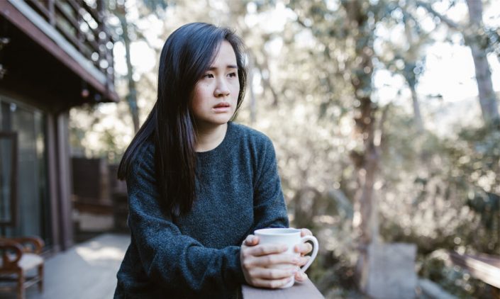 A girl is holding a cup and looking anxious and worry