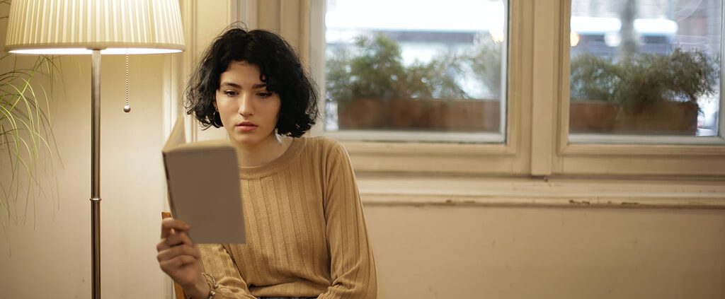 A girl is reading a book but is not focusing.