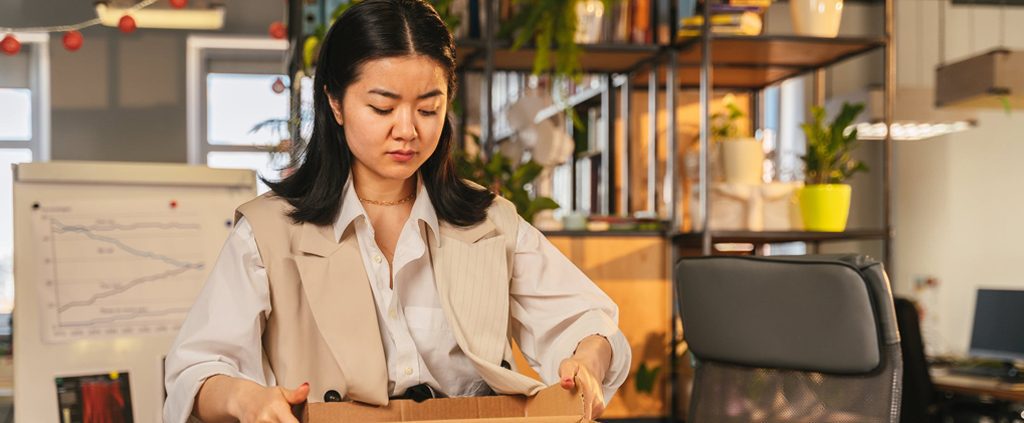 A woman sadly package her stuff into a box in office