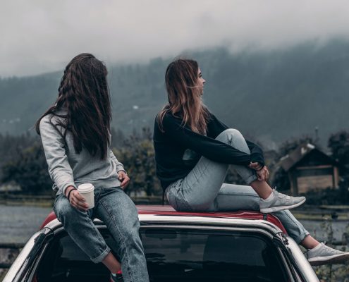two friends sitting on the car