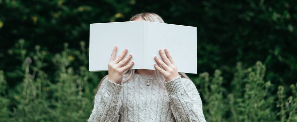 a girl use a book cover her face