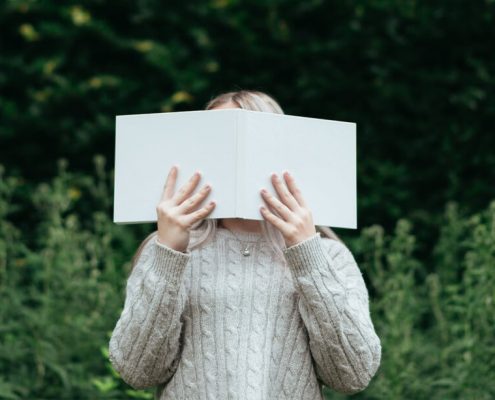 a girl use a book cover her face