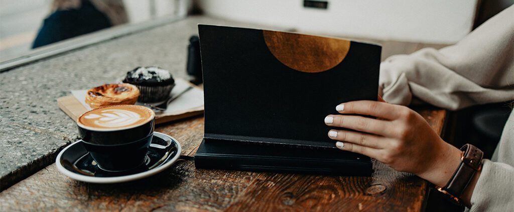 Image of a woman opening a journal at a cafe