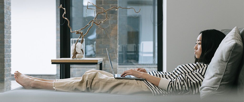 Image of woman working in bed with laptop