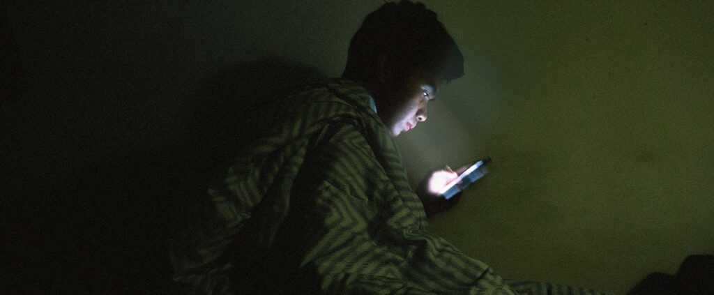 A man is scrolling the phone at bed time