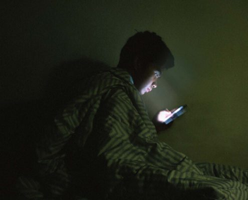 A man is scrolling the phone at bed time