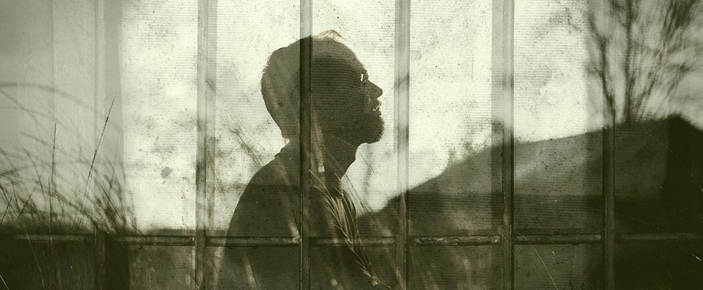 Silhouette of man looking up with courage overlaid with prison.