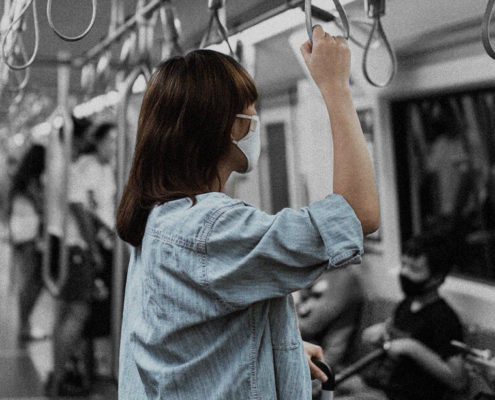 A woman is standing alone in the train like no one sees her