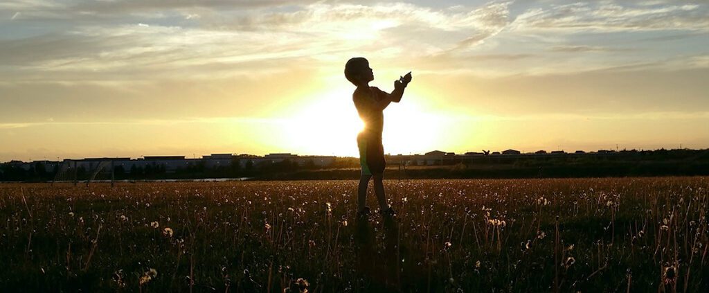 A child is praying in the middle of meadow