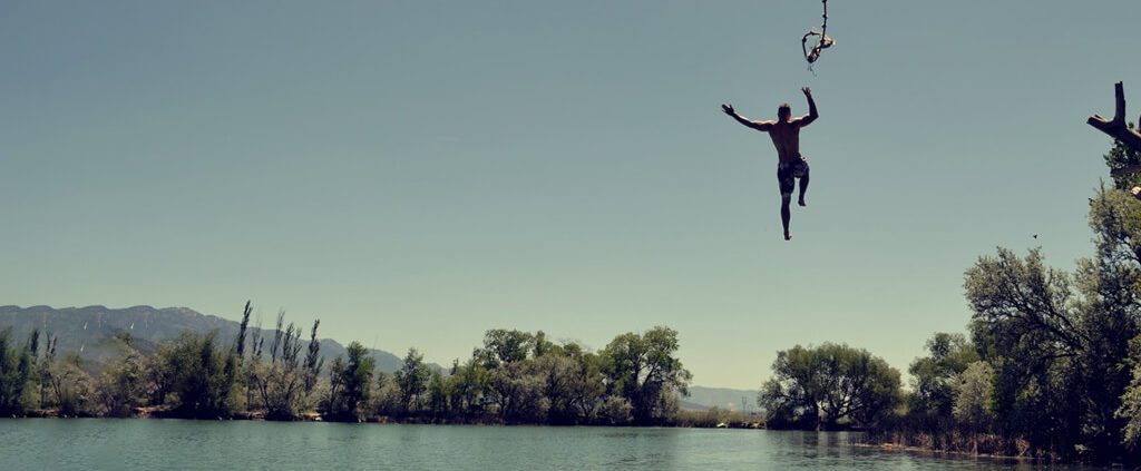 A man is releasing the rope and jumping into the water