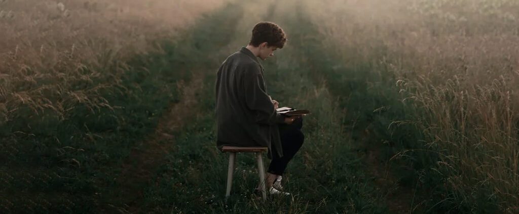 A man is reading bible in the middle of meadow