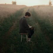 A man is reading bible in the middle of meadow