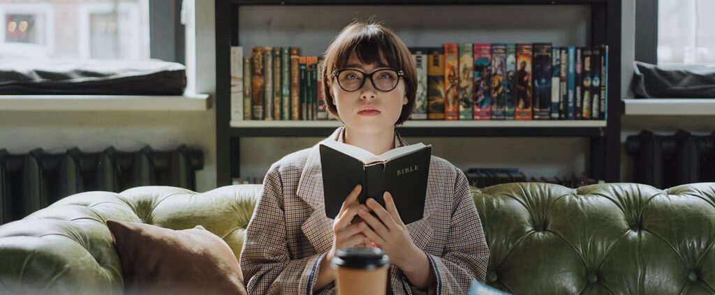 A woman is holding a bible but looking bored