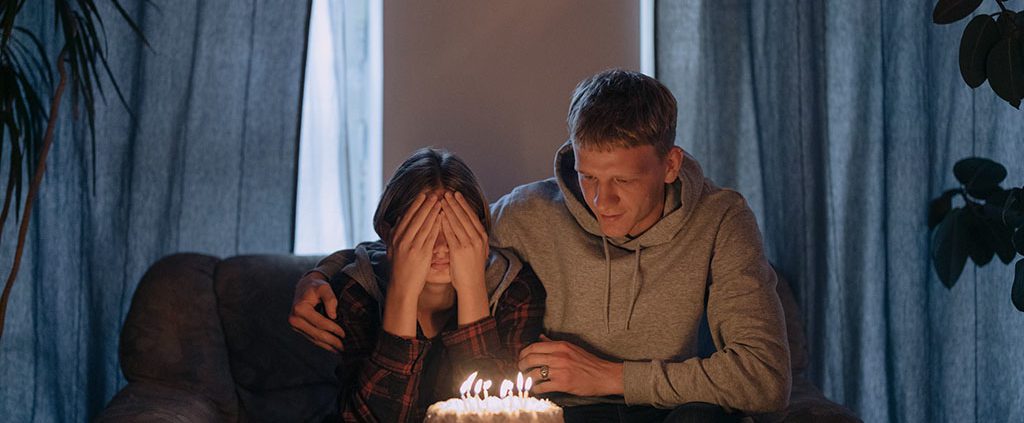 Man sitting with woman who is about to blow her birthday candles.