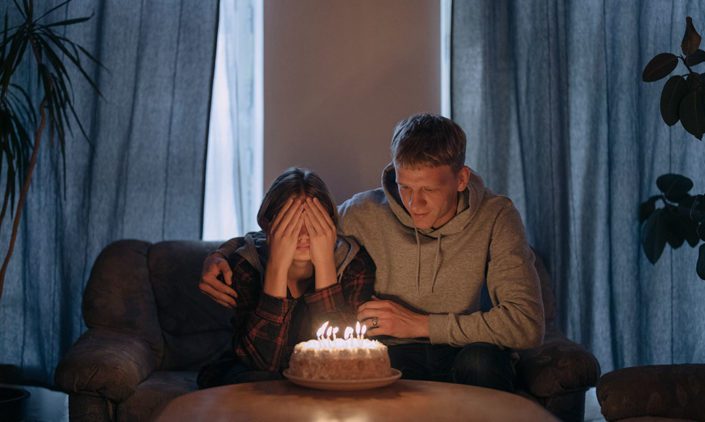 Man sitting with woman who is about to blow her birthday candles.