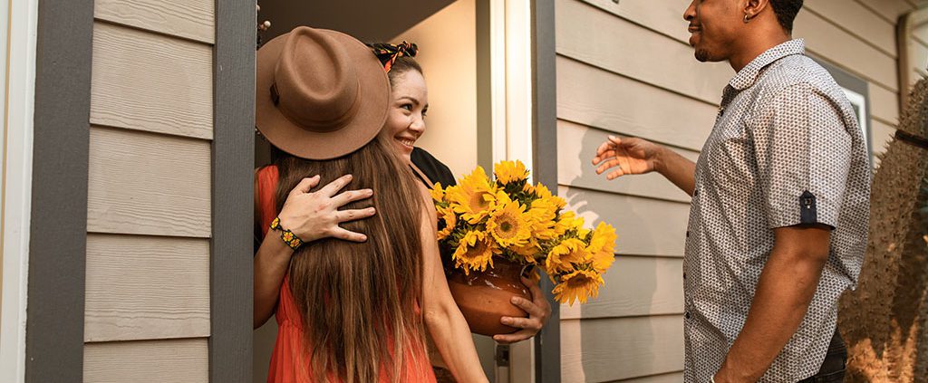 Friends show up in a woman's door bringing flowers