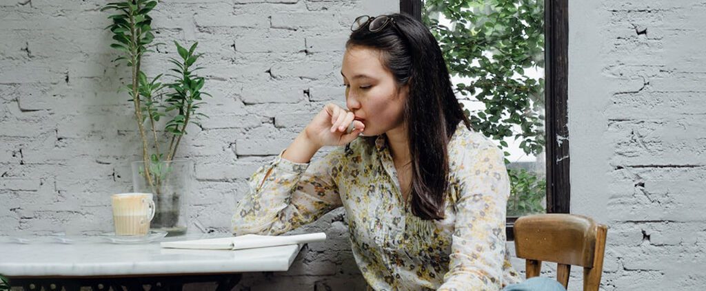 A woman is pondering while waiting someone in a cafe