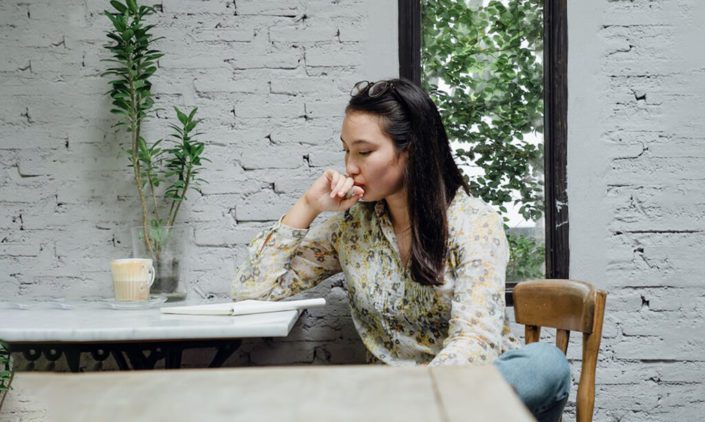 A woman is pondering while waiting someone in a cafe