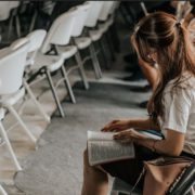 A woman is sitting quietly in the church and reading bible while listening to the sermon