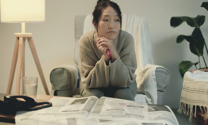 Woman in deep thought while browsing for jobs in the papers