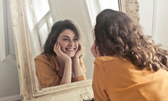 Woman looking at herself in the mirror looking content